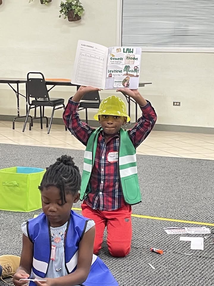 Student holding up his work in a hard hat